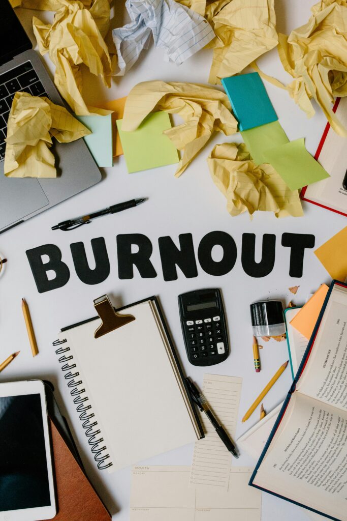 Symbolic image of burnout with crumpled papers and office supplies on a cluttered workspace.